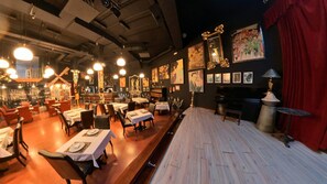 A restaurant with tables set for dining, a piano, and artwork on the walls. - Hotel Utopía (Benalup-Casas Vieja)
