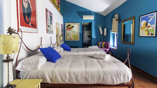 Habitación de hotel con dos camas, una araña y obras de arte en las paredes.