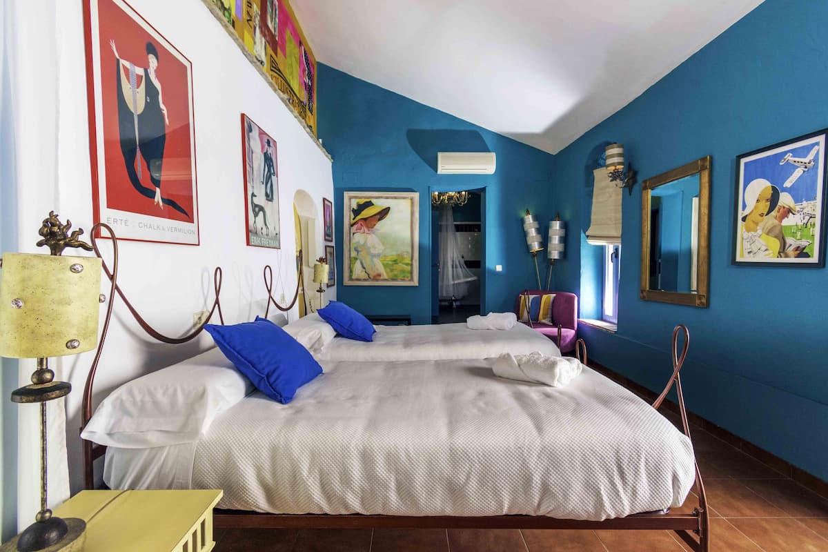 A hotel room with two beds, a chandelier, and artwork on the walls.