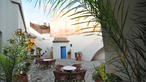 Un patio con suelo de piedra, sillas de mimbre y plantas en macetas.