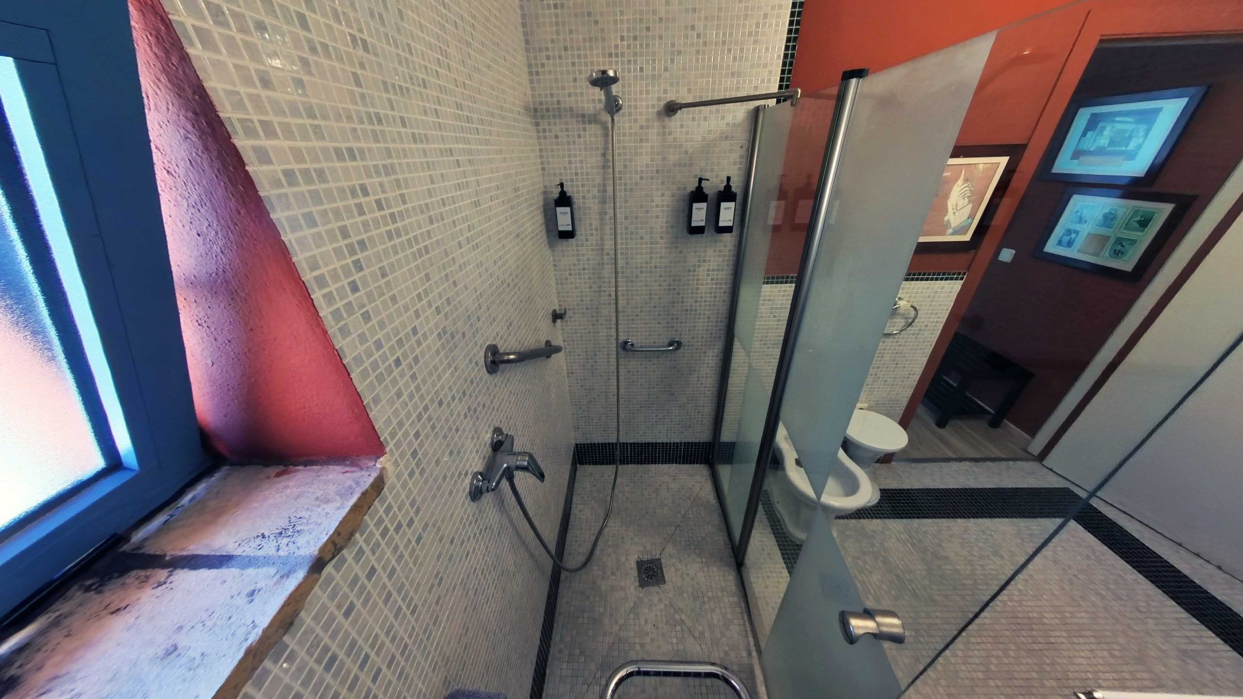 Douchegedeelte met een glazen scheidingswand, een handgreep en een betegelde wand.