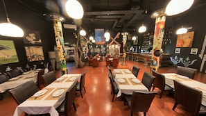A restaurant with tables set for dining, a bar area, and decorative pillars. - Hotel Utopía (Benalup-Casas Vieja)