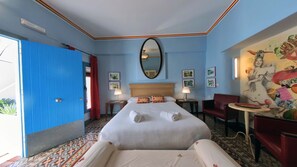 Una habitación de hotel con una cama, una silla, una mesa, un espejo y una pared decorada con cuadros.