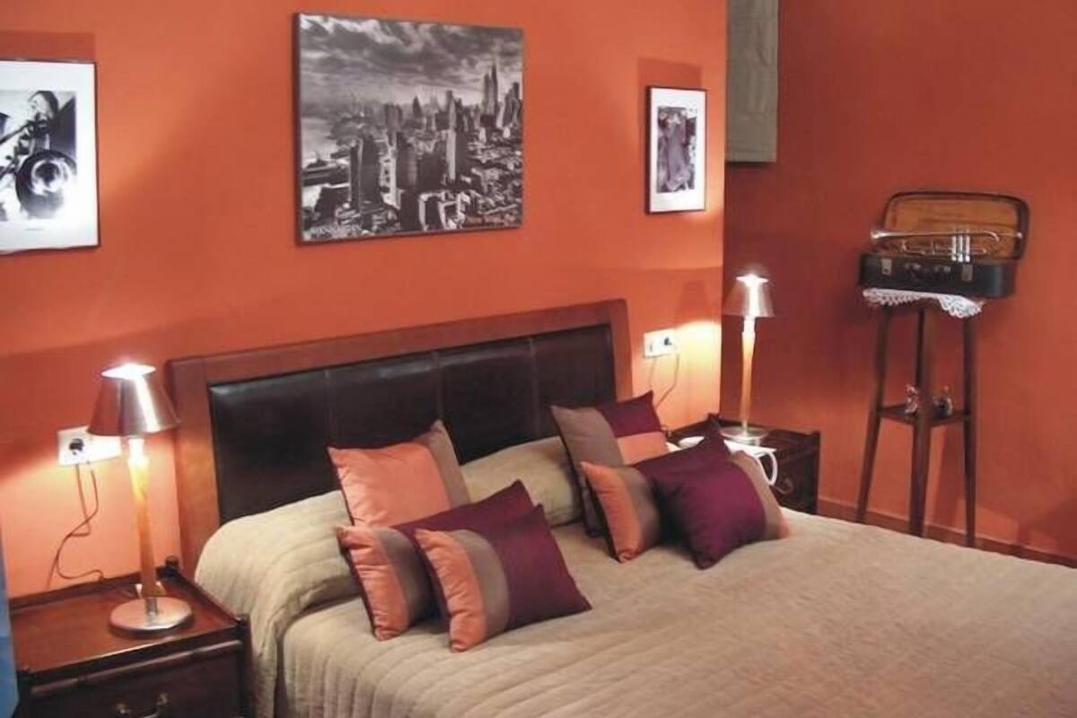 A bedroom with a bed, two bedside tables, a lamp, and a picture frame on the wall.