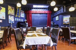A restaurant with a stage, red curtains, and framed pictures on the walls. - Hotel Utopía (Benalup-Casas Vieja)