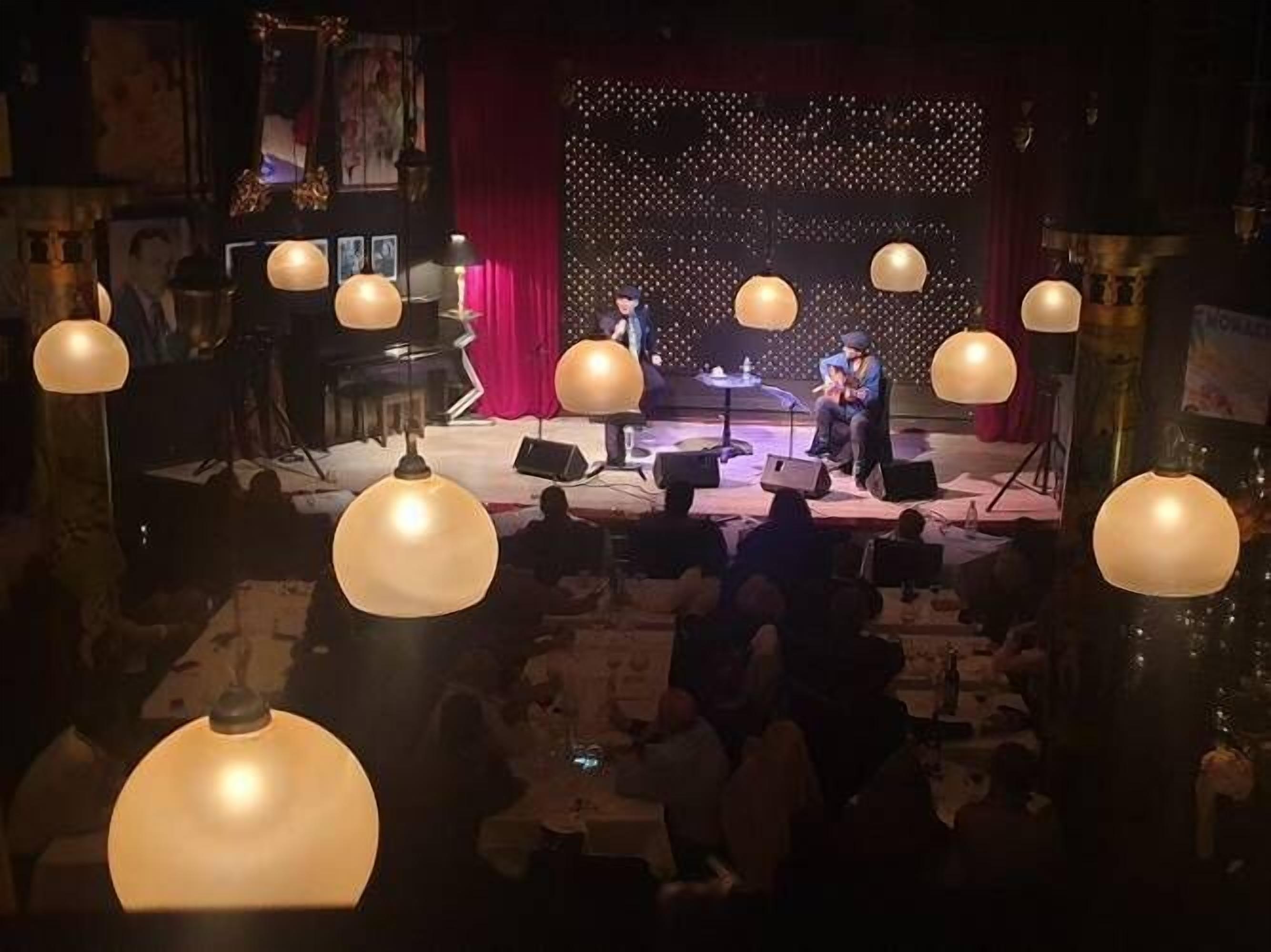 A stage with musicians performing, surrounded by tables and chairs.