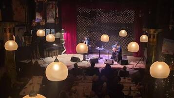 A stage with musicians performing, surrounded by tables and chairs.