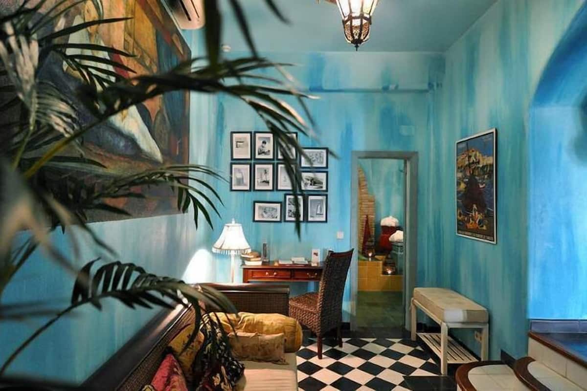 A room with a checkered floor, a desk with a lamp, a chair, and framed pictures on the wall.