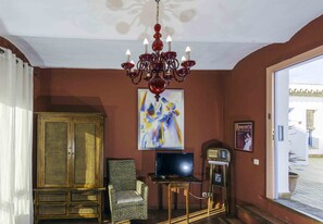 A room with a chandelier, a television, a cabinet, and a chair.
