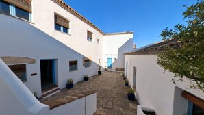 Un estrecho callejón adoquinado entre edificios blancos con puertas y ventanas azules.