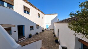 A narrow cobblestone alley between white buildings with blue doors and windows. - Hotel Utopía (Benalup-Casas Vieja)
