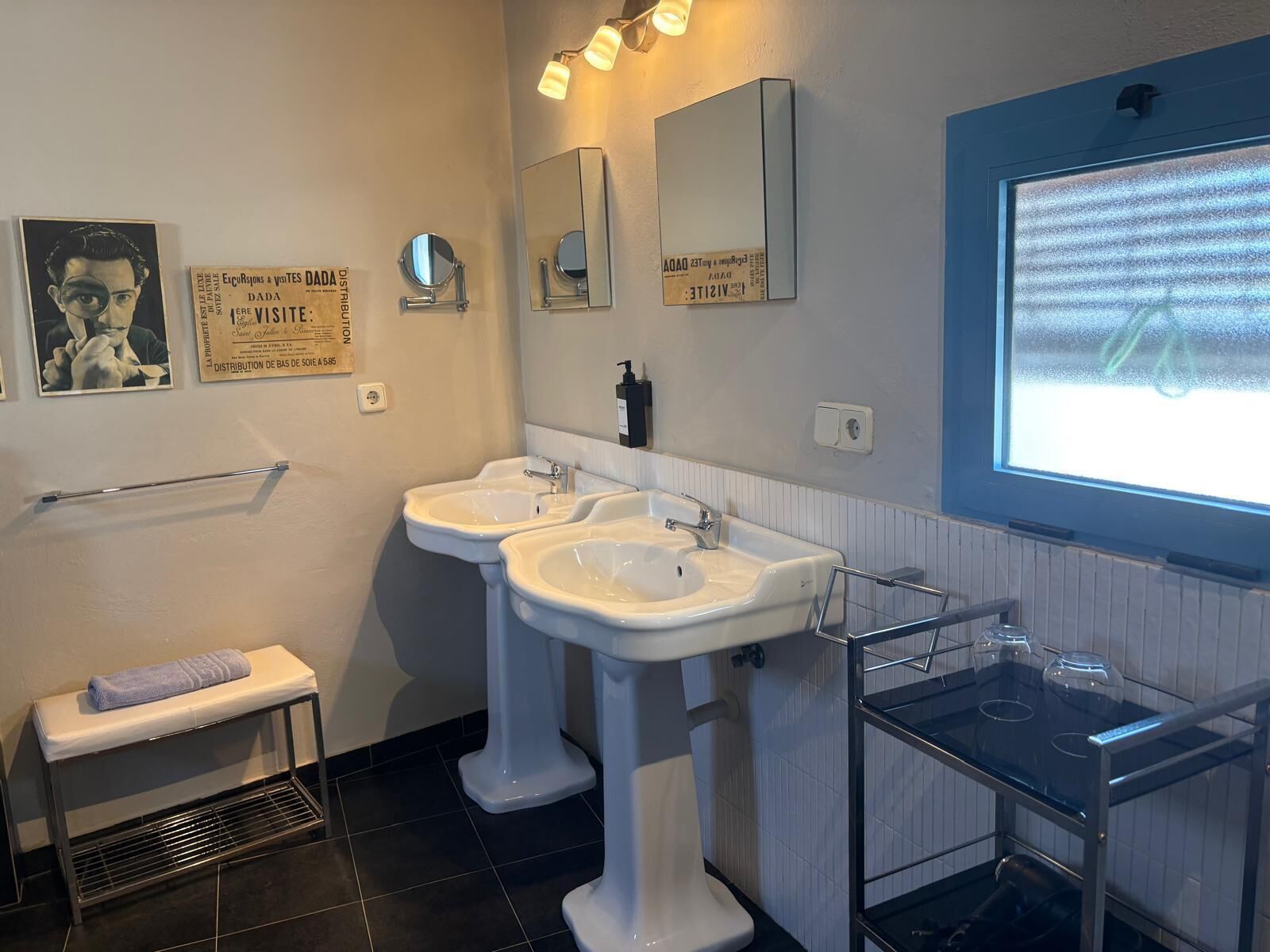 A bathroom with two sinks, a towel rack, a mirror, and a window with a view.