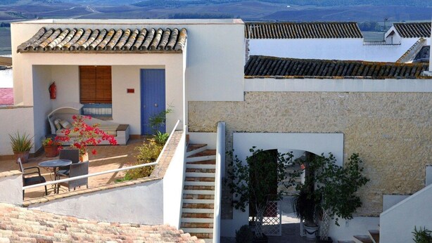 Un edificio residencial con patio, una escalera y vistas a montañas distantes.
