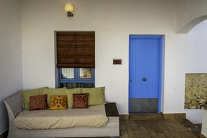 A room with a bed, a blue door, a window with blinds, and a wall-mounted light fixture. - Hotel Utopía (Benalup-Casas Vieja)