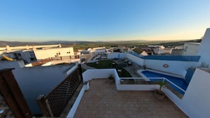 Eine Dachterrasse mit Pool, einem kleinen Garten und Blick auf die umliegenden Gebäude.