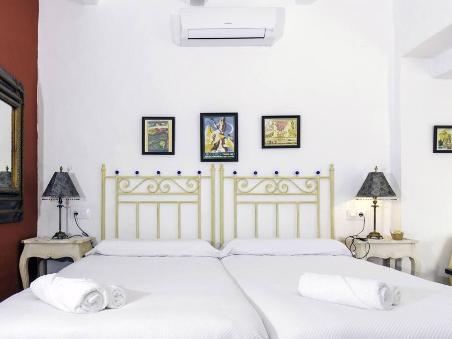 A hotel room with two beds, a large mirror, and three framed pictures on the wall.