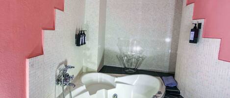 A bathroom with a large bathtub, a shower, and a sink.