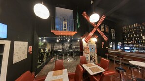 A bar area with stools, a high counter, and a mural on the wall. - Hotel Utopía (Benalup-Casas Vieja)