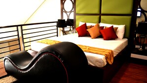 A bedroom with a bed, pillows, a headboard, a bedside table, and a lamp. - Executive Lofts by Mystique Lane (Bacolor)