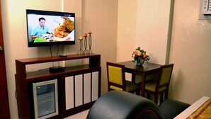 A living room with a television, a dining table with chairs, and a sofa. - Executive Lofts by Mystique Lane (Bacolor)