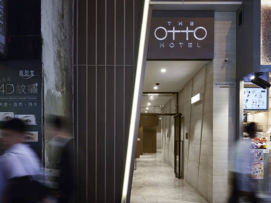 L’entrée de l’hôtel O+TO se distingue par son design moderne, avec une enseigne lumineuse bien visible et un intérieur épuré et bien éclairé, que l’on peut apercevoir à travers l’entrée.