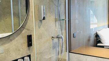 Un baño moderno con lavamanos de mármol negro, cabina de ducha de vidrio y un espejo grande.