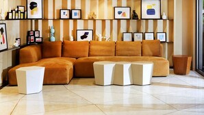 A modern living room with a sectional sofa, a coffee table, and a glass wall offering a view of outdoor furniture. - The Otto Hotel (Kowloon)