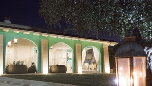 A building with a green facade, arched doorways, and a visible interior with a dining area. - Tenuta Donna Caterina (Mesagne)