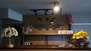 Una recepción con un cartel que dice 'HOSTEL', uno que dice 'BIENVENIDOS' y otro con la palabra 'WIFI'.