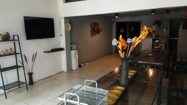 Un interior moderno con zona de comedor, televisor montado en la pared y un arreglo de plantas decorativas.