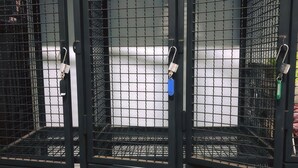 Una serie de jaulas metálicas con candados, probablemente para almacenamiento o seguridad.
