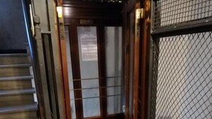 An elevator with a red carpet, a wooden door, and a metal mesh security gate. - Landlord in Trastevere (Rome)