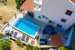 An aerial view of a modern building with a swimming pool, stone patio, and outdoor seating area. - Apartments Made 4U (Zupa dubrovacka)