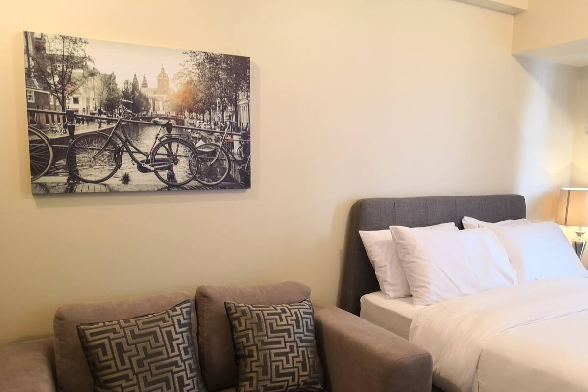 Ein Hotelzimmer mit Bett, einer Couch und einem Wandbild einer Brücke mit Fahrrädern.