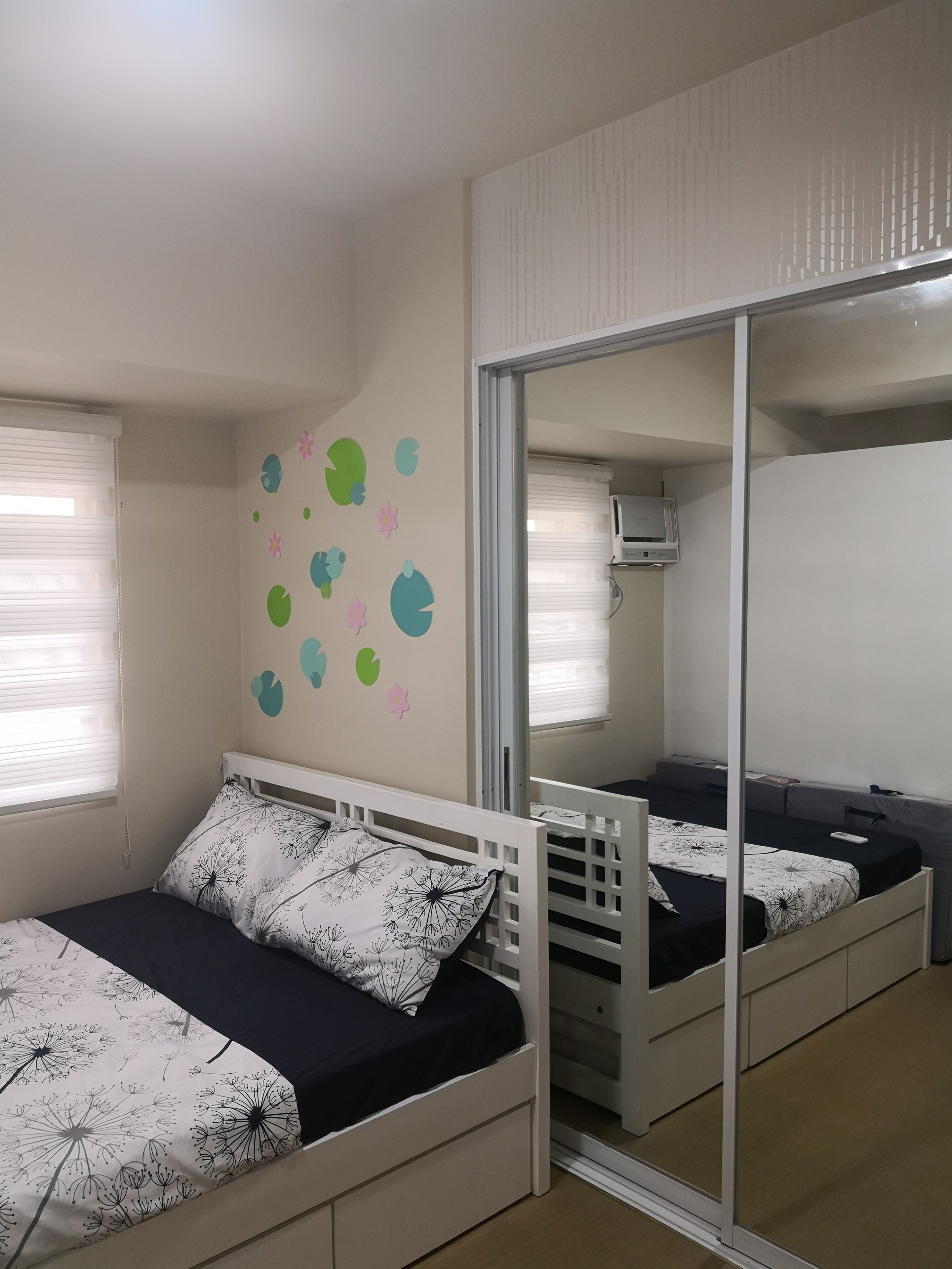 Una camera da letto con due letti, un grande specchio e un muro con adesivi decorativi.
