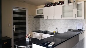 Una cocina moderna con encimera negra, armarios blancos, un lavamanos de acero inoxidable y una guirnalda decorativa sobre los armarios.