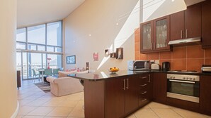 Een moderne keuken met donkere houten kastjes, een roestvrijstalen oven en een groot raam dat voor natuurlijk licht zorgt.