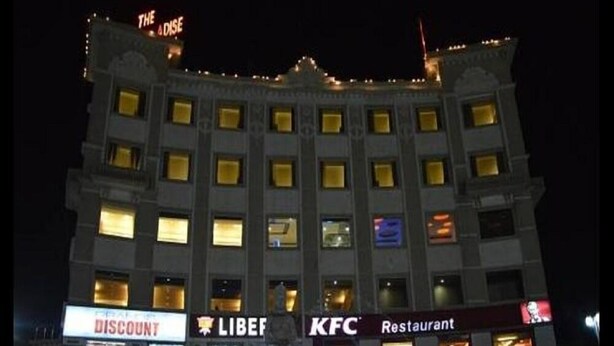 A multi-story hotel with illuminated signage for 'The Oasis' at the top, 'DISCOUNT' on the ground floor, 'LIBEF' and 'KFC' restaurants on the second floor. - The Royal Paradise (Karnal)