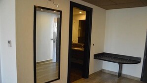 A hallway with a mirror, a door leading to a bathroom, and a small sink area. - The Royal Paradise (Karnal)