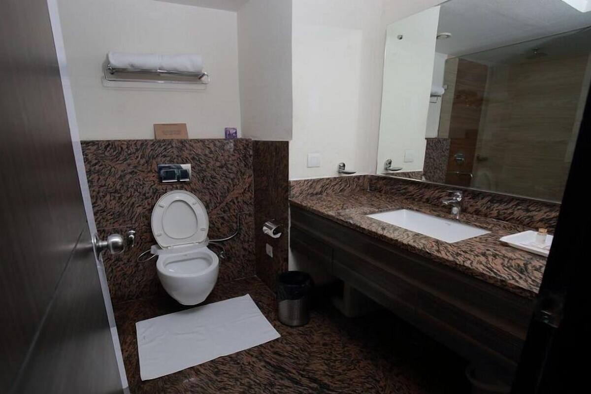 A modern bathroom with a toilet, sink, and mirror.