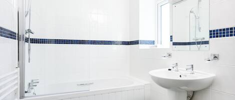 A modern bathroom with a bathtub, a sink, and a glass-enclosed shower area.