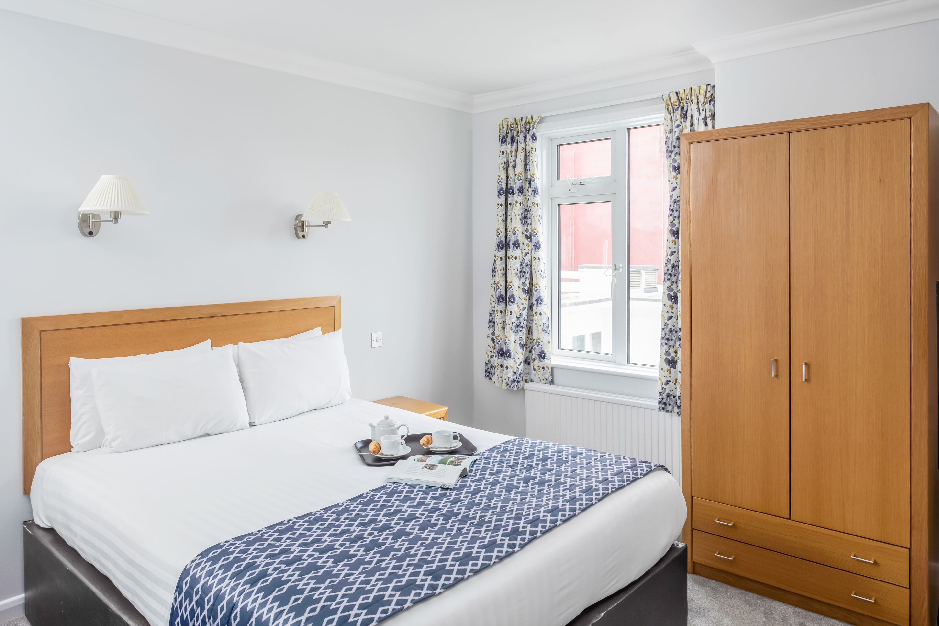 A neatly arranged bedroom with a bed, bedside table, and a wardrobe.