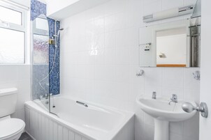 Un baño moderno con bañera, lavamanos e inodoro.
