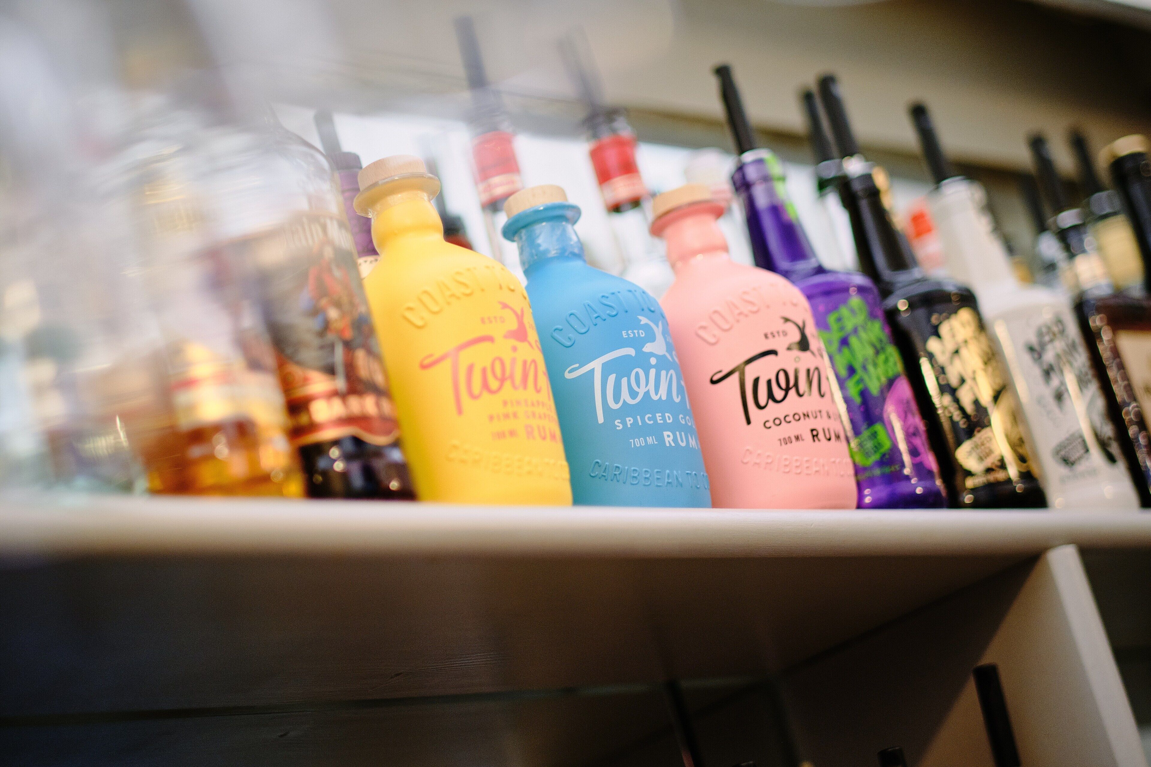 A shelf with various bottles of rum, including brands like 'Coast to Coast' and 'Twin'.