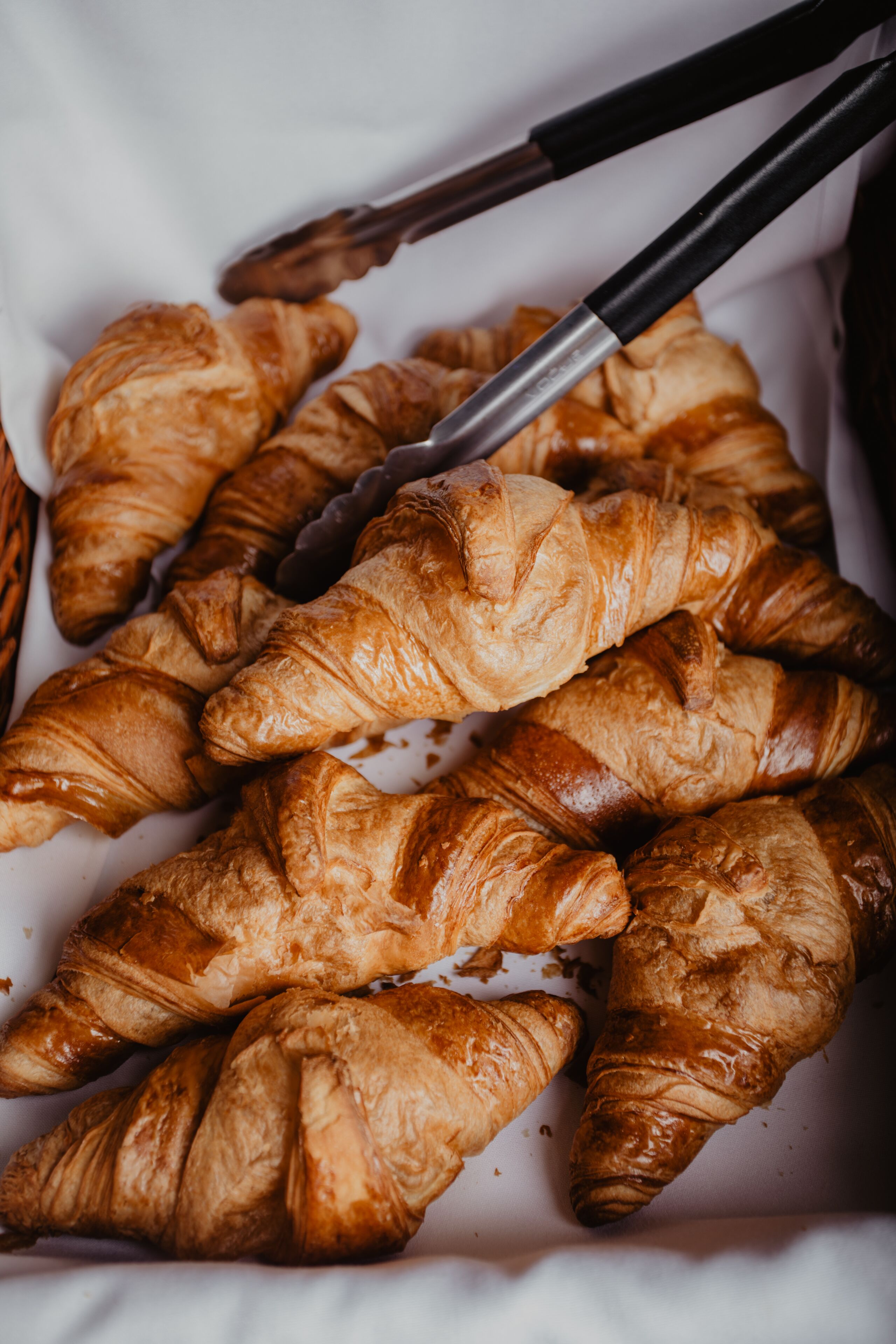 A tray of golden-brown croissants arranged on a white surface.