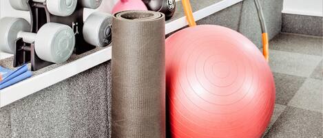 A home gym with exercise equipment including dumbbells, kettlebells, a yoga mat, and a medicine ball.