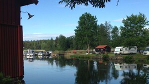 Un terrain de camping pour véhicules récréatifs situé au bord d’un lac, avec des bateaux, un chalet et un bâtiment rouge.