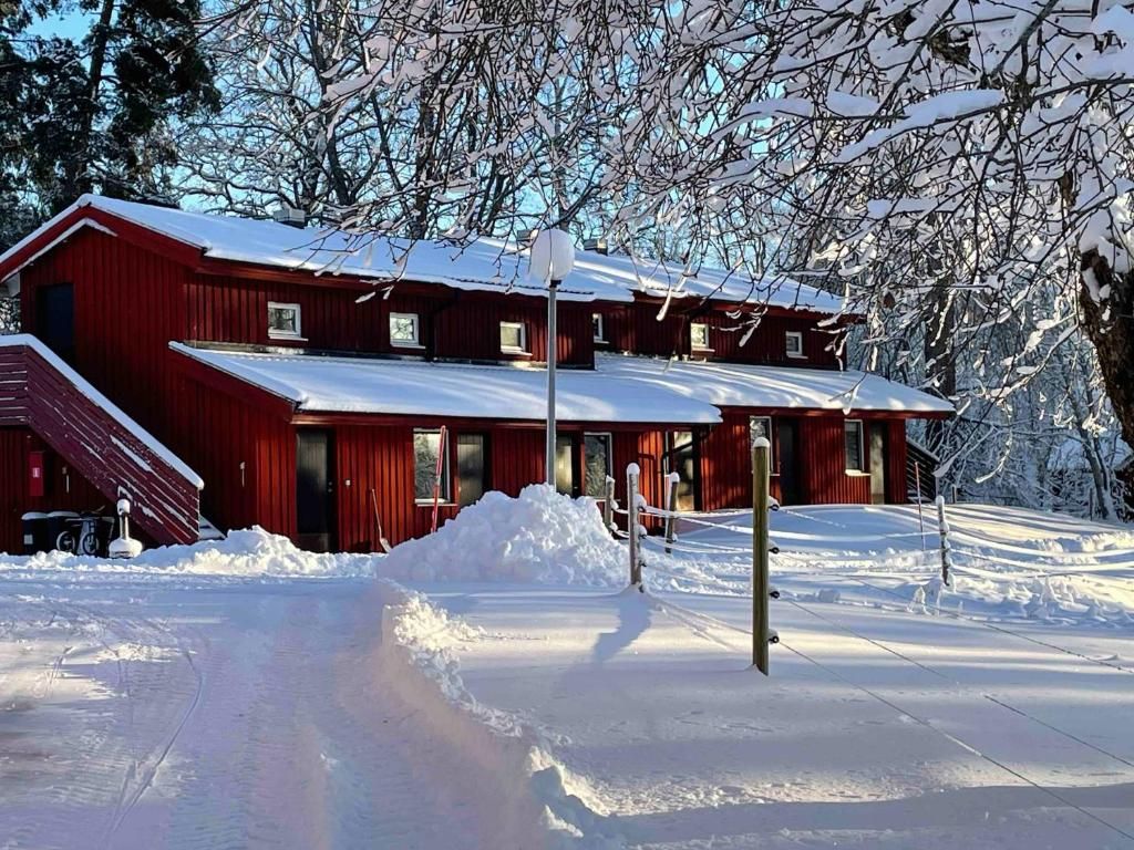 Un bâtiment rouge avec de nombreuses fenêtres et un toit recouvert de neige, entouré de neige.