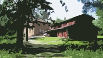 A building with a sloped roof, surrounded by trees and a grassy area.