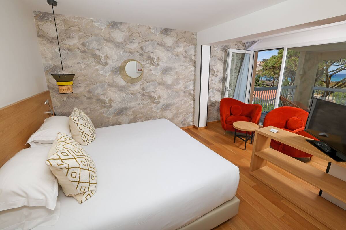 Un dormitorio moderno con una cama grande, televisión y balcón con vistas.